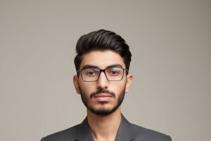 Ultra-realistic, 8K editorial studio portrait of a young man with dark, slicked-back hair, wearing a structured dark gray blazer and a minimalist black watch. His arms are crossed, conveying confidence.