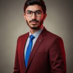 Ultra-realistic, high-definition editorial portrait of a young man with dark, slicked-back hair and a subtle beard, wearing a tailored, deep burgundy suit jacket with a lapel pin. Focus is sharp on the face, skin, and fabric texture.