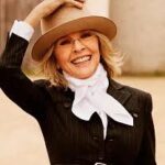 Diane Keaton smiling in her signature wide-brimmed hat and tailored suit, representing her timeless Hollywood style.
