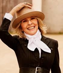 Diane Keaton smiling in her signature wide-brimmed hat and tailored suit, representing her timeless Hollywood style.